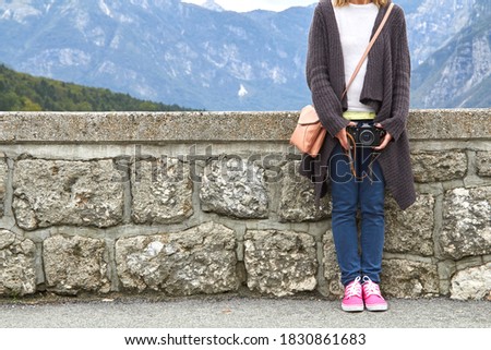 Young caucasian woman holding vintage retro camera outdoors.