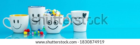 Four cups with funny faces on a color background. The concept of a friendly company, a big family, meeting friends for a cup of tea or coffee. Smiles on white coffee mug