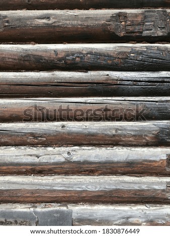 fragment of the wall of an old wooden building with cracked and burnt logs