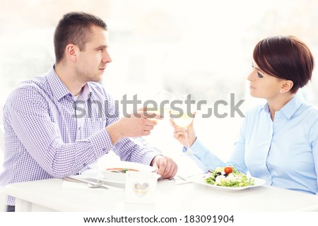 A picture of a young happy couple sitting in a restaurant and drinking wine