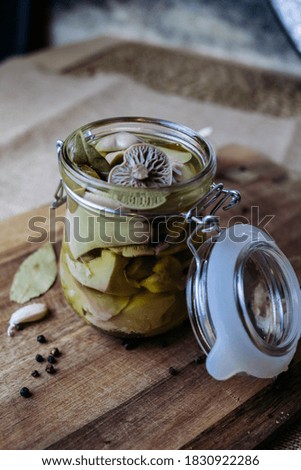Pickled canned mushrooms in a jar on a cutting Board. Close up. Blurry background.