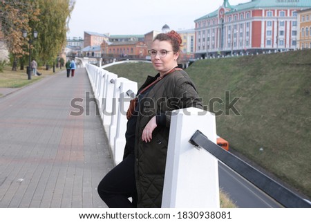 Lovely red-haired woman posing on an autumn walk