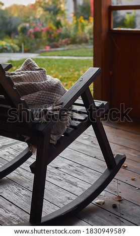 wooden rocking chair on the front porch with warm knitted plaid