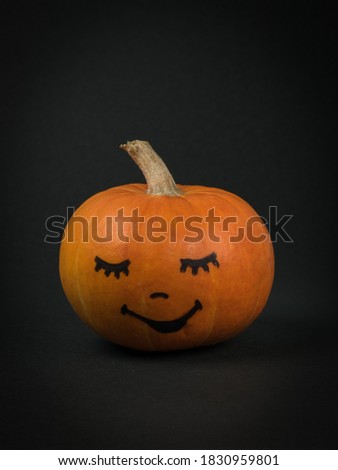 Pumpkin with a cute face on a black background. Halloween party.