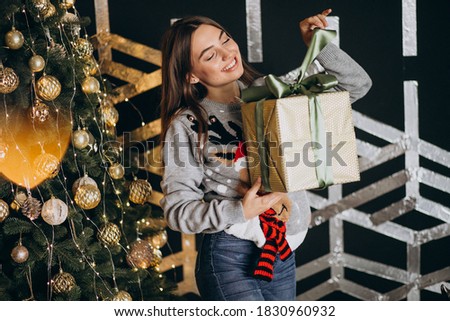 Young woman unpacking christmas present by the christmas tree