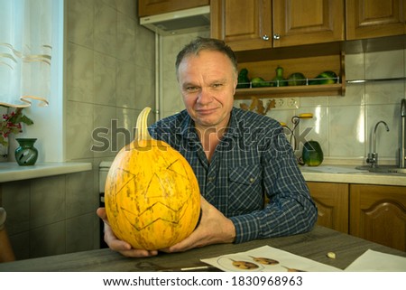 The pumpkin is ready for slicing. The man are happy with their work and laugh and joke .