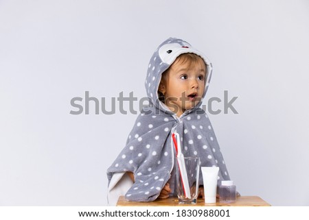 Toddler brushing teeth. Kid with toothpaste and brush. Dental hygiene care. Healthy daily routine for children. Child after shower wearing a pajama and bathrobe. Health concept on white background