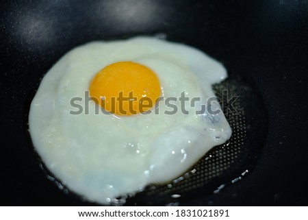 Choose a close-up focal point of the fried egg sprinkled with salt on the pan.