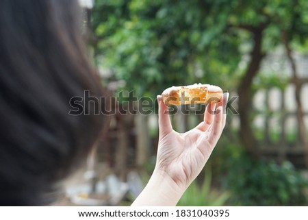 A picture of a woman holding a donut with a bite