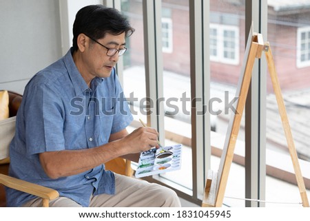 senior asian man painting at home