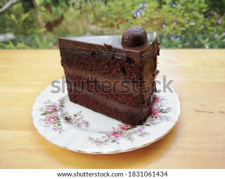 
Chocolate Cake In a white plate with a flower pattern Placed on the floor of a wooden table.