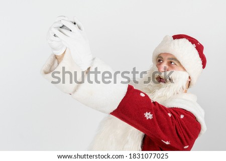 Christmas and New Years concept. Santa Claus poses, makes a selfie on a mobile phone. Isolated background