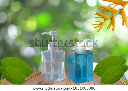 White and blue hand sanitizer or alcohol gel pump bottle on a stick with a natural green background.