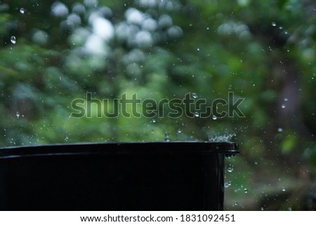 Rainy weather on the terrace. The rain falls into the bucket and creates splashes
