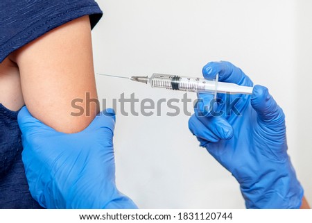 The girl is vaccinated in her hands on a white background in the hospital. Routine vaccination against flu and colds. Prevention of the spread of coronavirus infection. Royalty-Free Stock Photo #1831120744