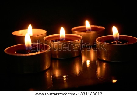 Burning candles on a black background, selective focus, romantic setting, atmosphere, shot with shallow depth of field.