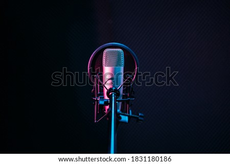 Studio microphone and pop shield on mic in the empty recording studio with copy space. Performance and show in the music business equipment. Royalty-Free Stock Photo #1831180186