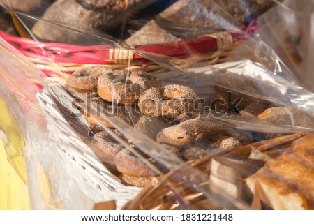 Homemade biscuits ciambelli with sugar on top and other bakery packed in baskets with transparent polyethylene film on the shell. Sweets in the market. Protective film on food as anti covid measure. 