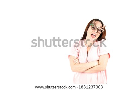 Excited young woman smiling and crossing her arms while wearing reindeer glasses against a white background
