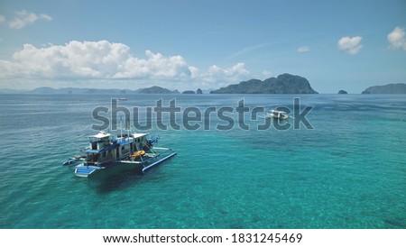 Aerial Philippines ocean bay: boat, ship at turquiose water surface. Local cruise tour for tourist on vessel at sea bay of El Nido Island, Visayas Archipelago, Asia. Tropical seascape in drone shot