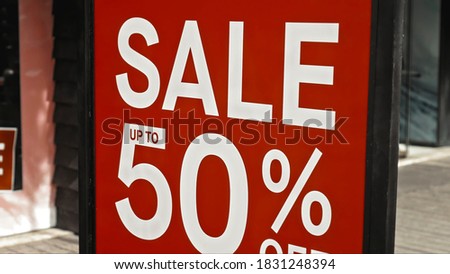 Red sign hanging on a glass window with the inscription sale up to 50% off