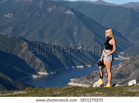 Young women at the top of a mountain holding a digital camera