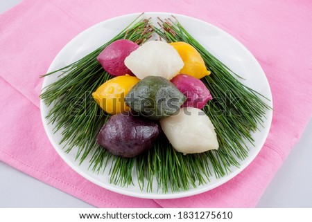 Various colored Songpyeon(half-moon-shaped rice cake) with pine needles on a dish, South Korea. It is Korean traditional food eaten during New Year's Day or Korean Thanks Giving Day Royalty-Free Stock Photo #1831275610