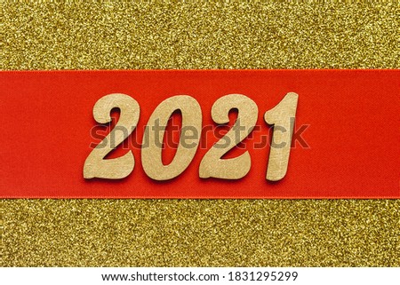 Festive sparkling background. Red ribbon with golden 2021 new year sign.Winter holiday celebration banner. Copy space.