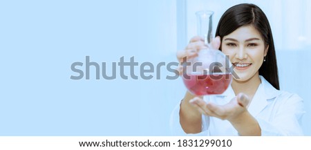 Portrait of beautiful scientist holding a round bottom bottle filled with purple solution.