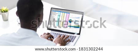 African American Man Using Spreadsheet Reports On Laptop Computer