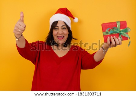 Good job! Portrait of a happy smiling Middle aged woman wearing Christmas hat giving two thumbs up gesture standing indoors. Positive human emotion facial expression body language. Funny girl
