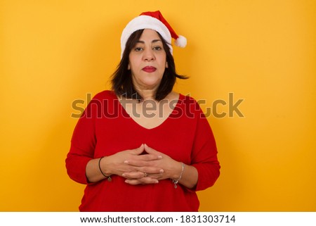 Business Concept - Portrait Middle aged woman wearing Christmas hat  holding hands with confident face isolated over gray Background.