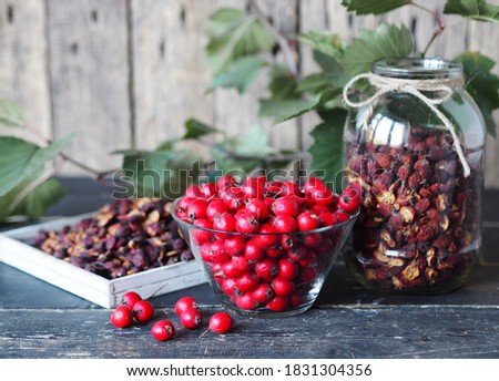 Useful properties of hawthorn berries. Harvesting of dried hawthorn for future use. Fresh red and dried hawthorn on a wooden background.Alternative traditional medicine using hawthorn. Royalty-Free Stock Photo #1831304356