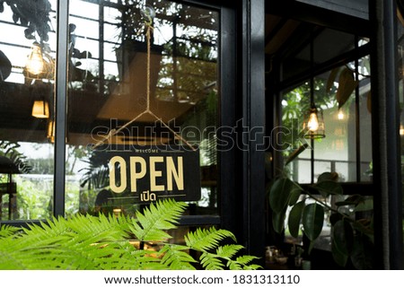 Text "OPEN" on black sing side the door with tree font