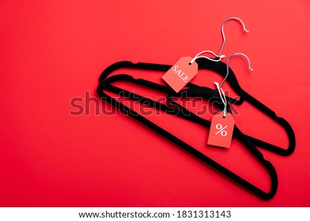 Black Friday sale concept. Two hangers with red labels on red background. Fashion clothes store discount, special offer, outlet. 