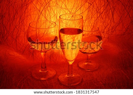 Three glasses of water on a red abstract background. Close up, contour light, stylish background. Beautiful picture for a poster. Art.