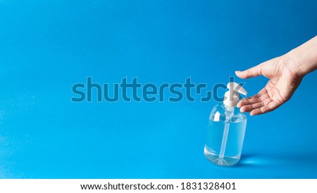 Anti bacterial gel poured on hand on blue background.Large image with copy space