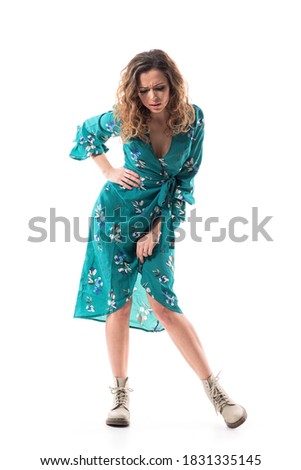 Displeased upset young stylish woman looking down at floor seeing stains. Full body portrait isolated on white background