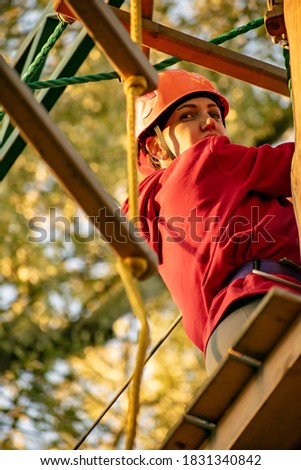 A young girl overcomes obstacles in the rope park. Vertical photography.
