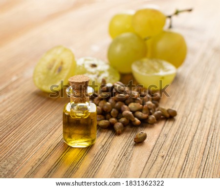 Grape oil seed in small vintage bottle. Heap of grape seeds with green slices and cold press organic essential oil, tincture, extract, infusion on wooden rustic background closeup