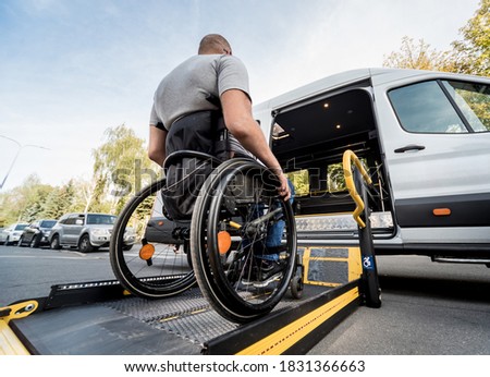 A man in a wheelchair moves to the lift of a specialized vehicle  Royalty-Free Stock Photo #1831366663