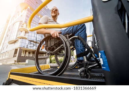 A man in a wheelchair on a lift of a vehicle for people with disabilities
