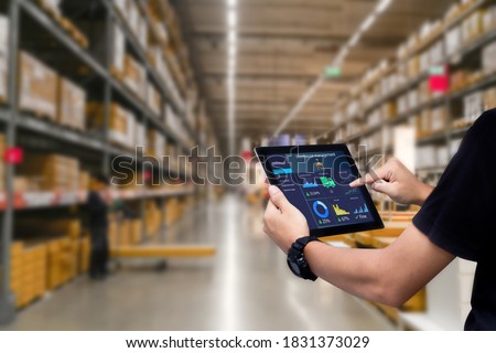 Smart warehouse management system.Worker hands holding tablet on blurred warehouse as background Royalty-Free Stock Photo #1831373029