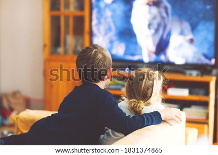 Cute little toddler girl and school kid boy watching animal movie or movie on tv. Happy healthy children, siblings during coronavirus quarantine staying at home. Brother and sister together. no face