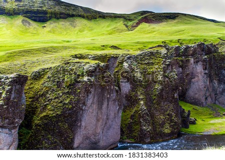 The beautiful canyon in Iceland - Fyadrarglyufur. Cloudy summer day. Cliffs covered with green moss stand along a stream with glacial water. The concept of eco and photo tourism