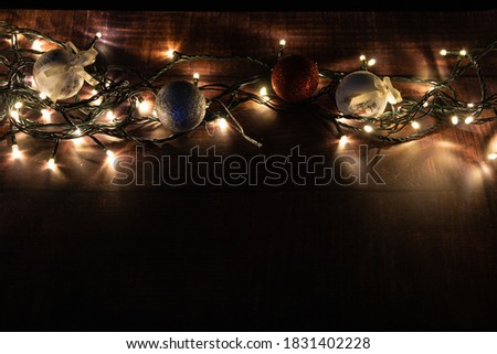 christmas balls with lights on a wooden base. christmas decoration. low key photography