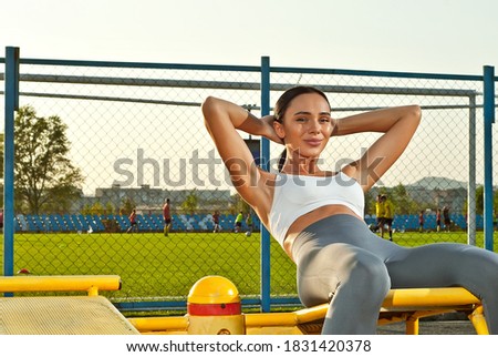Woman shakes the press on a background of sunset. Sports ground near the football field.