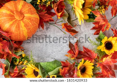 Autumn background: orange pumpkin, yellow sunflowers, orange and red leaves, floral frame for design. Soft focus.