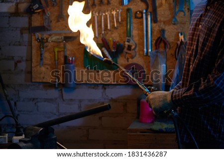 Unrecognizable worker holding welding torch turned on Royalty-Free Stock Photo #1831436287