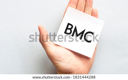 Businessman's hand in a pink shirt sleeve holding paper business card with text BMC sharp , closeup isolated over white background